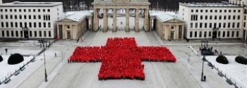 Mehr Inofmationen zum freiwilligen Engagement in unserem Ortsverein. Foto: Arm einer DRK-Pflegerin vor einem Mensch-Ärger-dich-nicht-Spiel